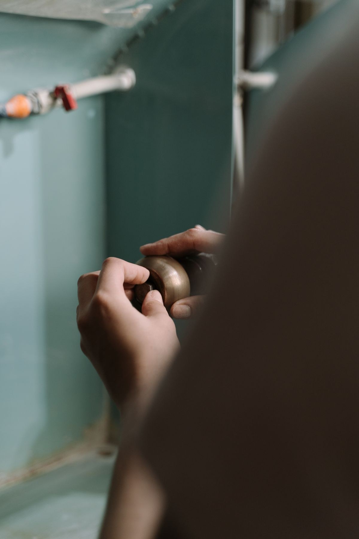 Hands adjusting a pipe fitting under a sink